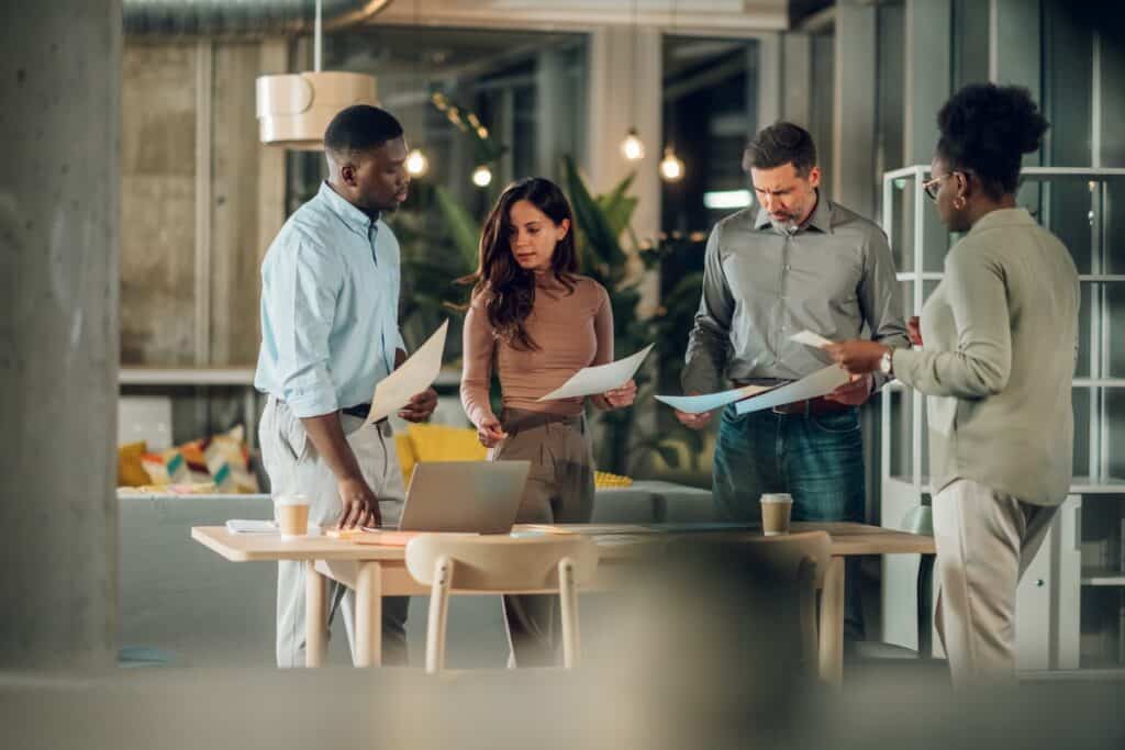 Équipe de professionnels collaborant autour d'une table dans un bureau moderne, examinant des documents.